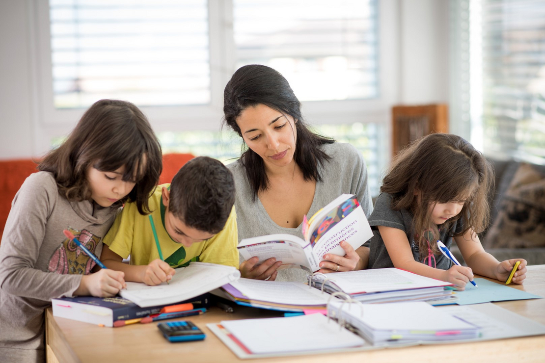 Une étudiante d'UniDistance Suisse étudie pendant que ses trois enfants font leurs devoirs