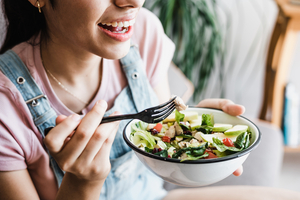 Une jeune femme mange un bowl de salade